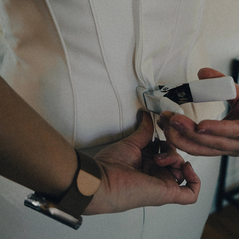 Person using a dress clamp to adjust a white corset top