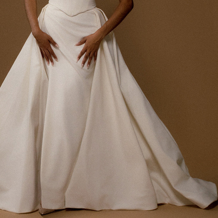 Bottom of a white wedding dress on a brown background