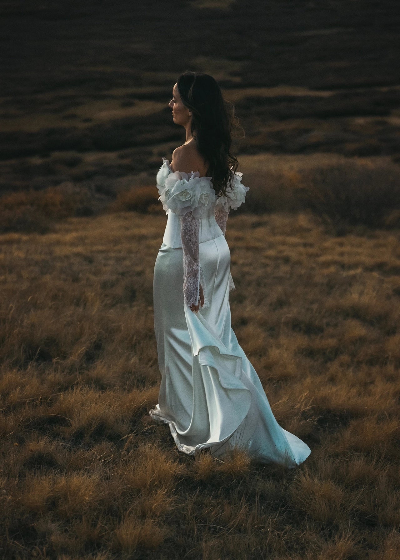 Woman in a white dress standing in a field with a dark background
