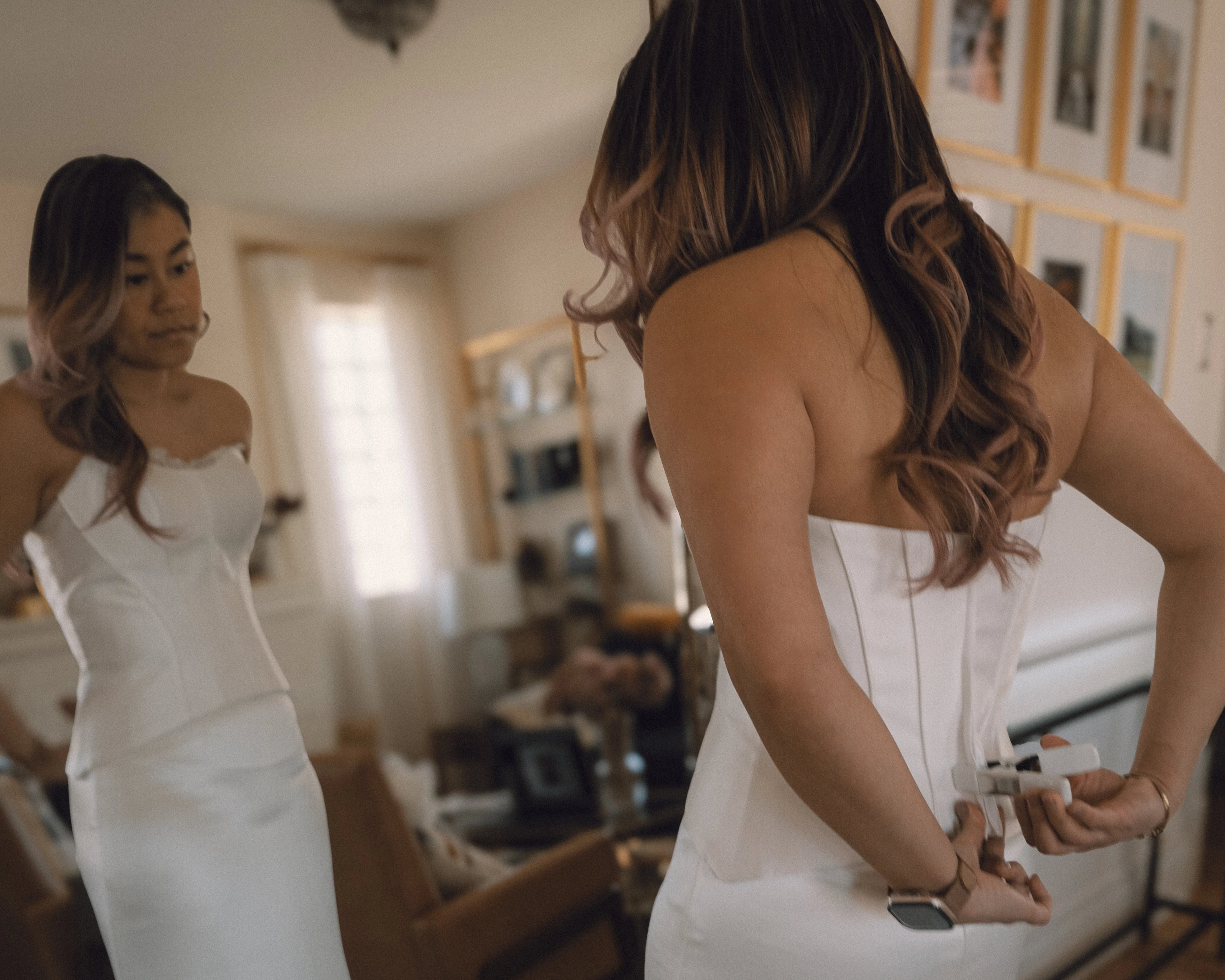 Bride trying on modern satin wedding dress in front of mirror at home during The Real Bride try-on experience