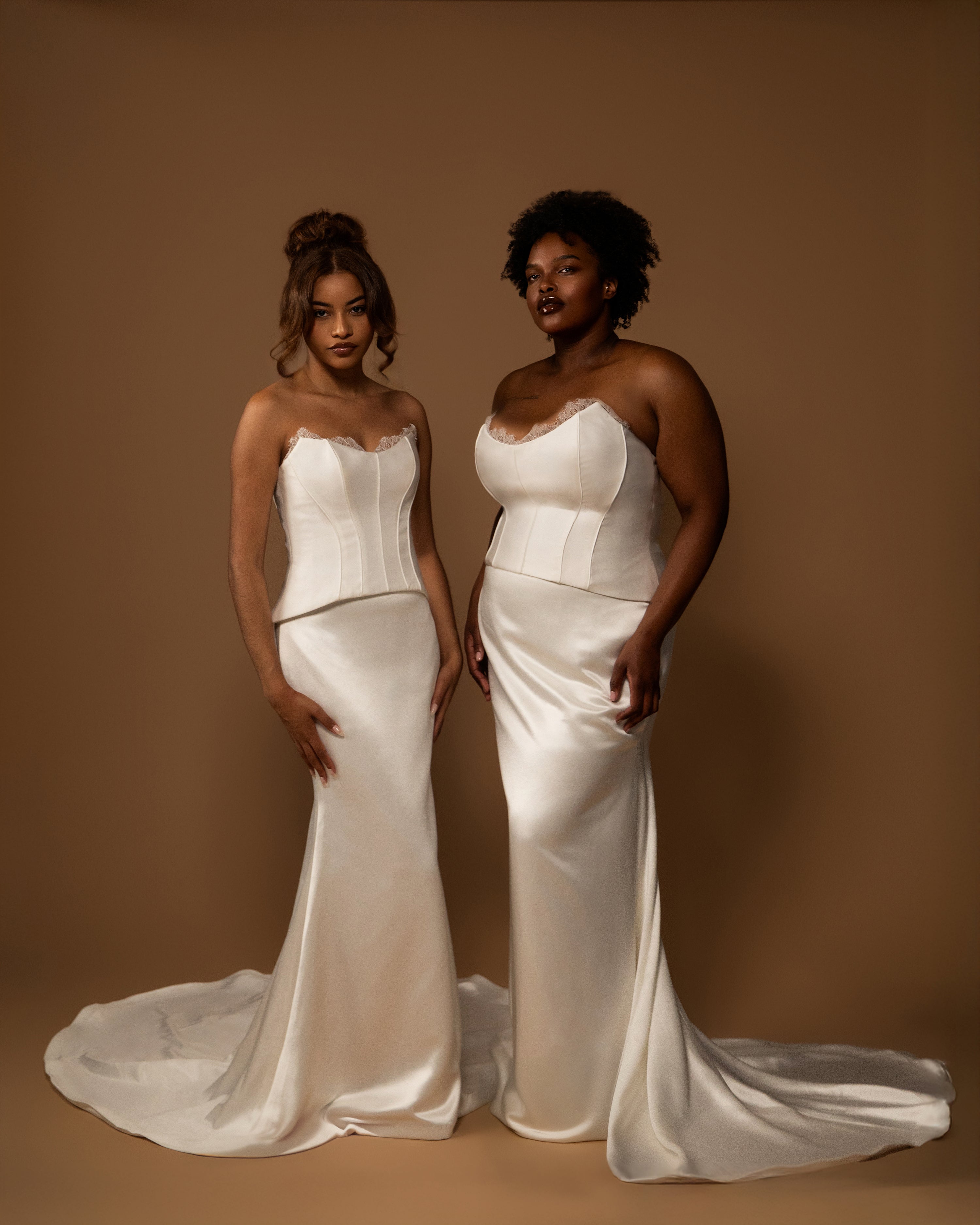 A Straight size and plus size bride wearing white strapless bridal sets standing against a brown background