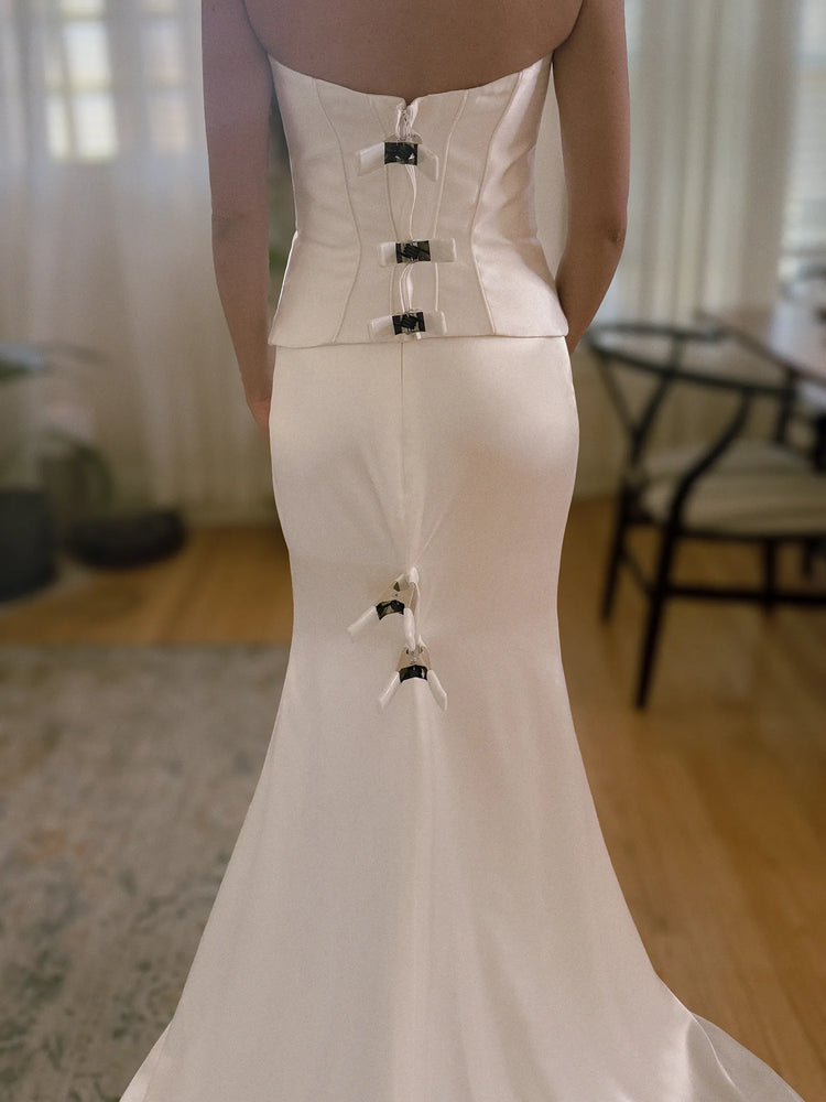 White strapless gown with dress clamps on a blurred indoor background