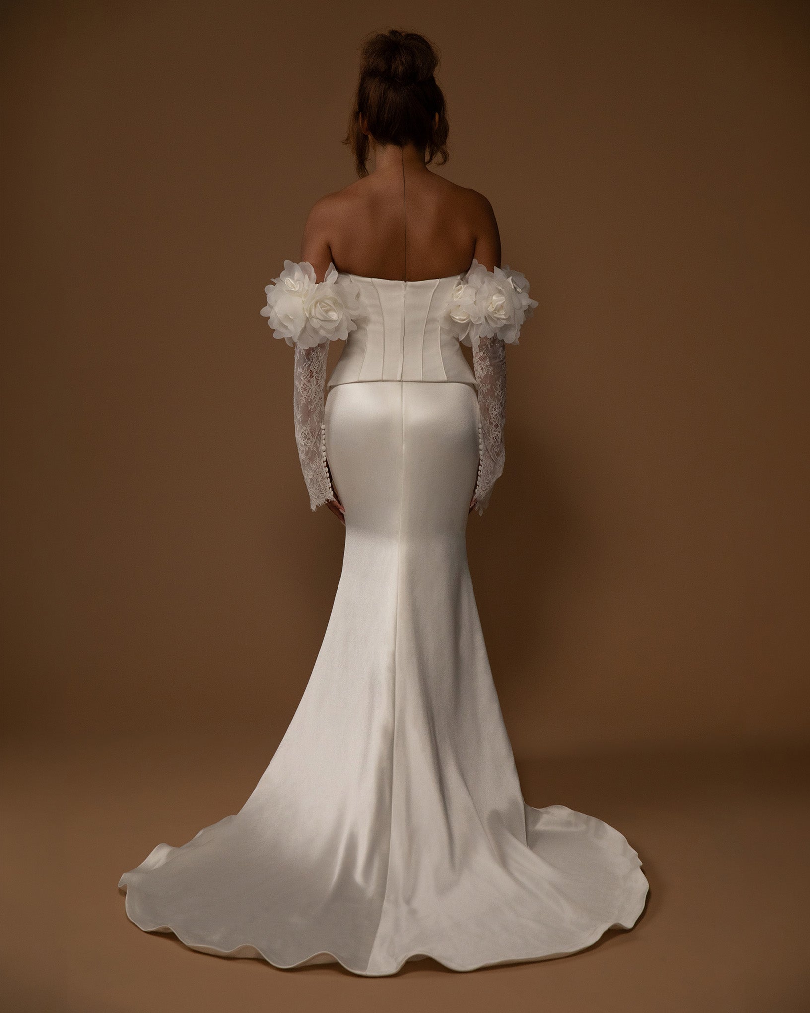 White wedding dress with floral removable sleeves details on a brown background