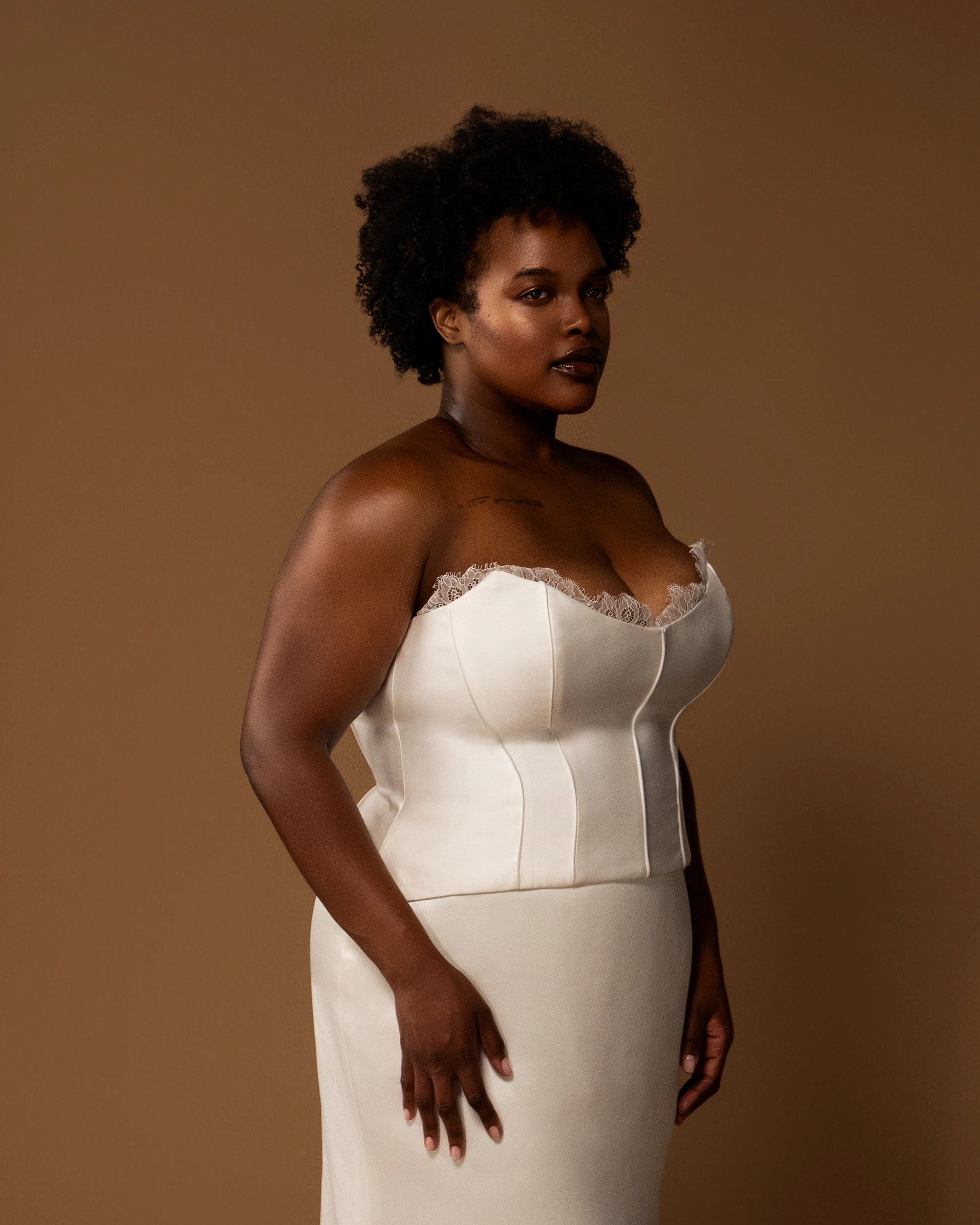 Woman wearing a white strapless wedding gown against a brown background